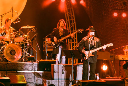 Kenny Loggins in concert with band members wearing Old Frontier Frock Coat